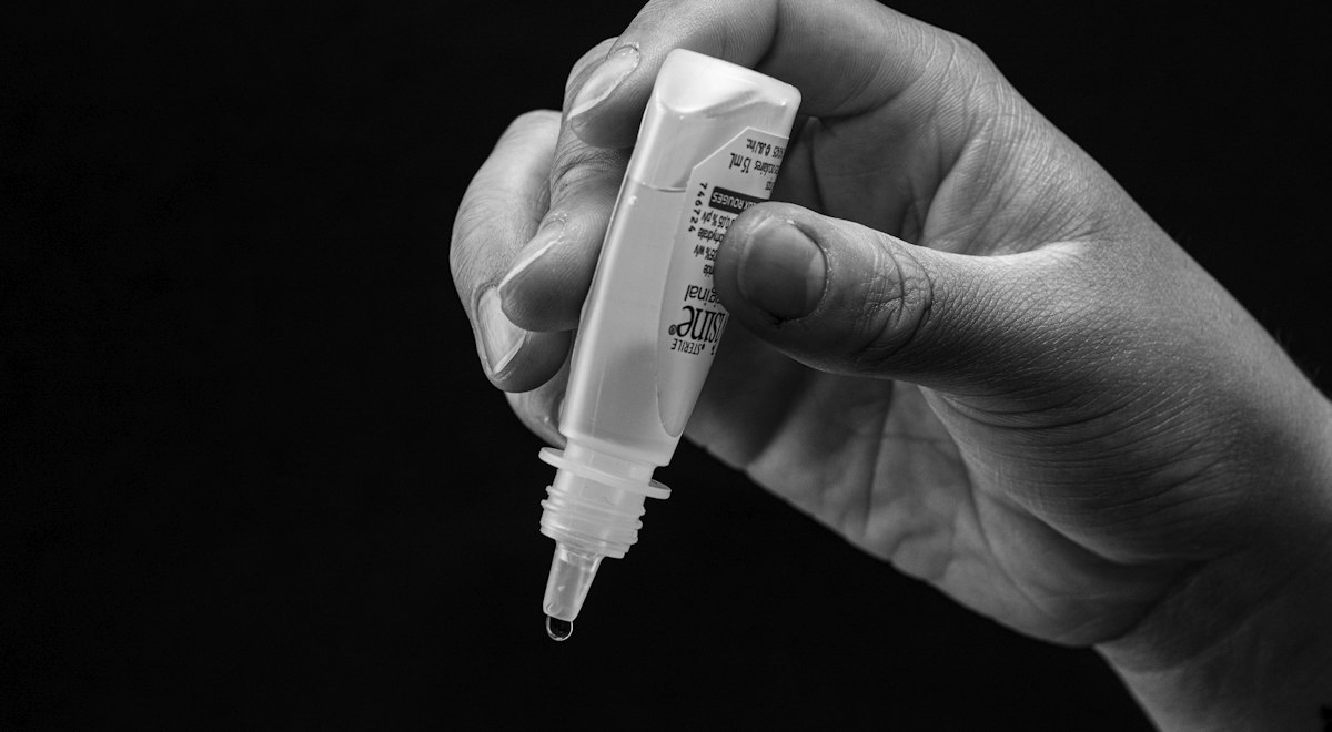 Hand holding a bottle of lubricating eye drops for dry eye relief