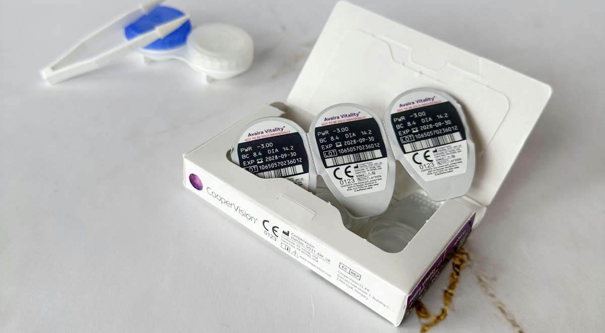 Contact lenses in their packaging with a case and tweezers for contact lens care