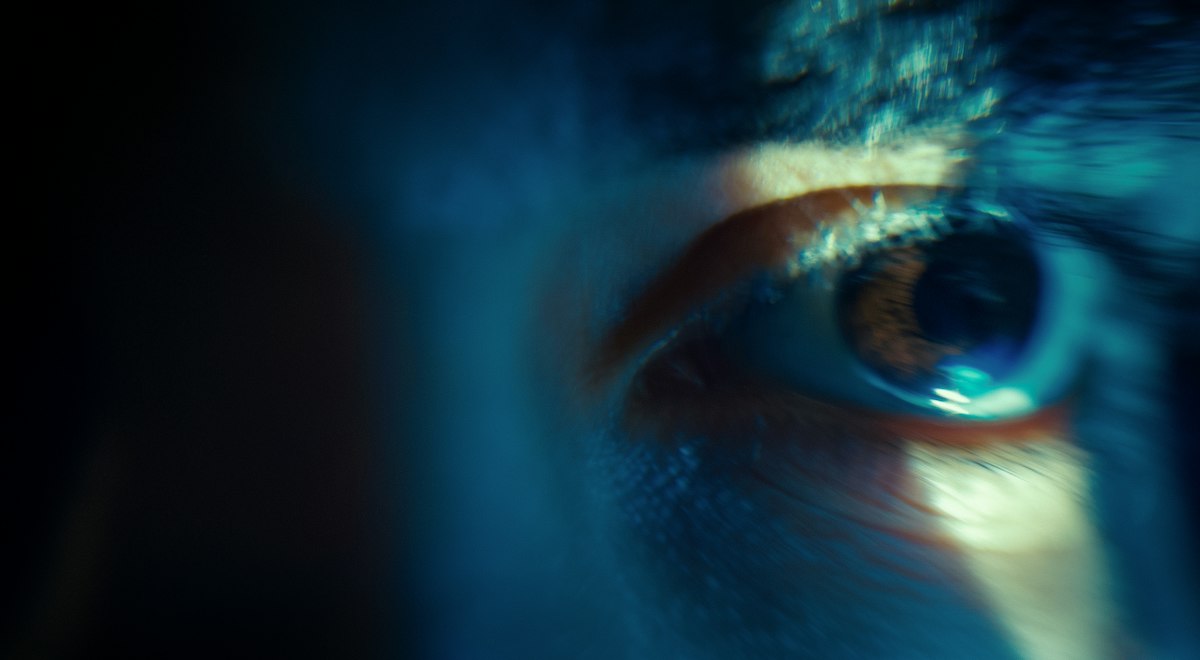 Close-up of a human eye lit in blue and warm light, representing flapless laser vision correction