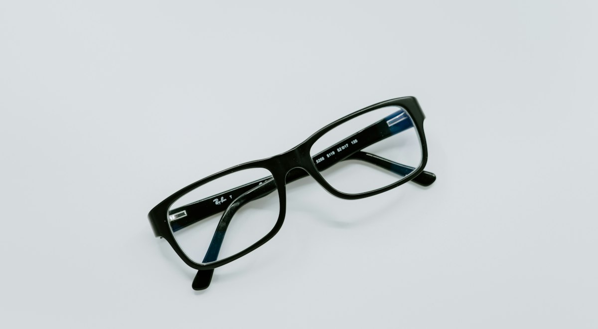 Black-framed eyeglasses on a light surface, representing vision correction options such as ICL and LASIK