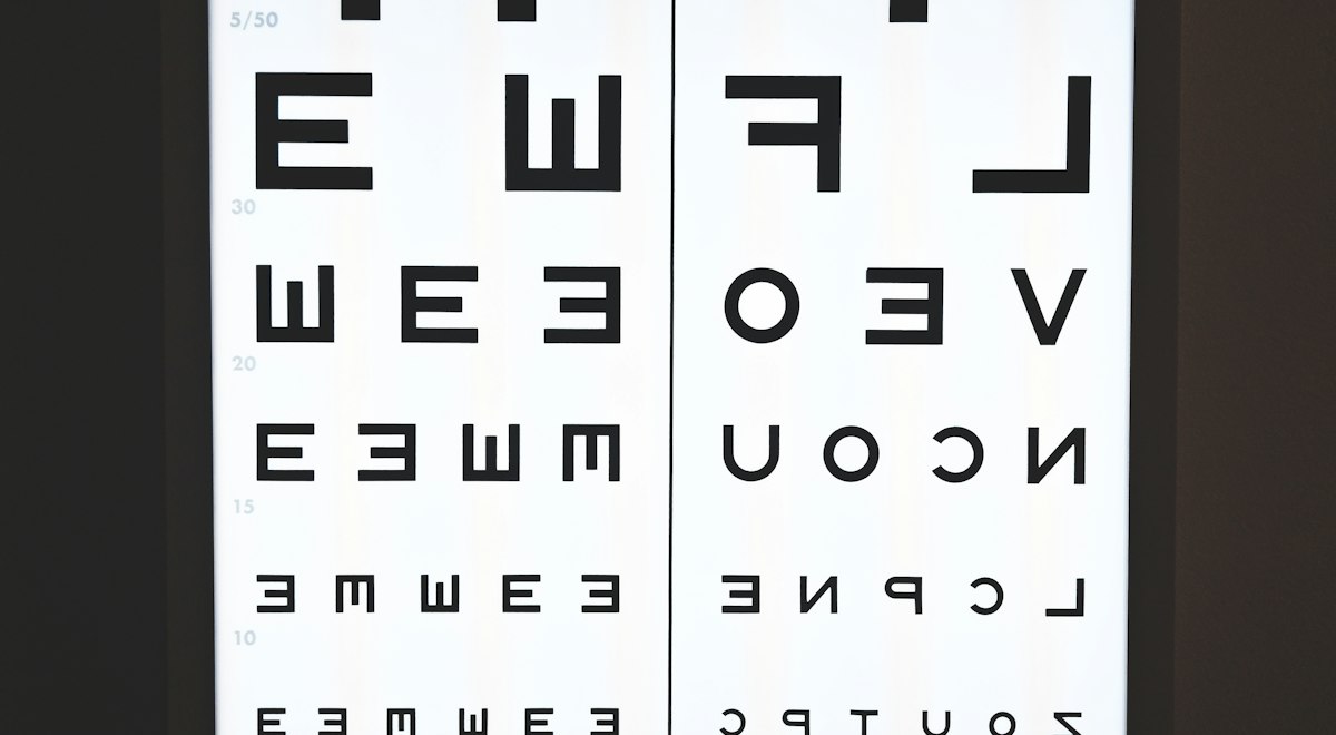 Doctor pointing to a visual acuity eye chart during an eye examination